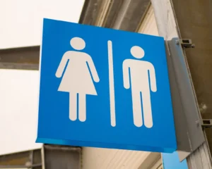 a sign for restrooms hanging outside on a metal pole