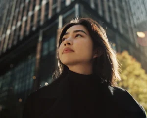 a young woman looking looking off into the distance in front of a building