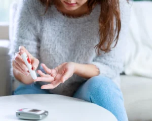 a woman taking a sample of her blood for an blood sugar measurement