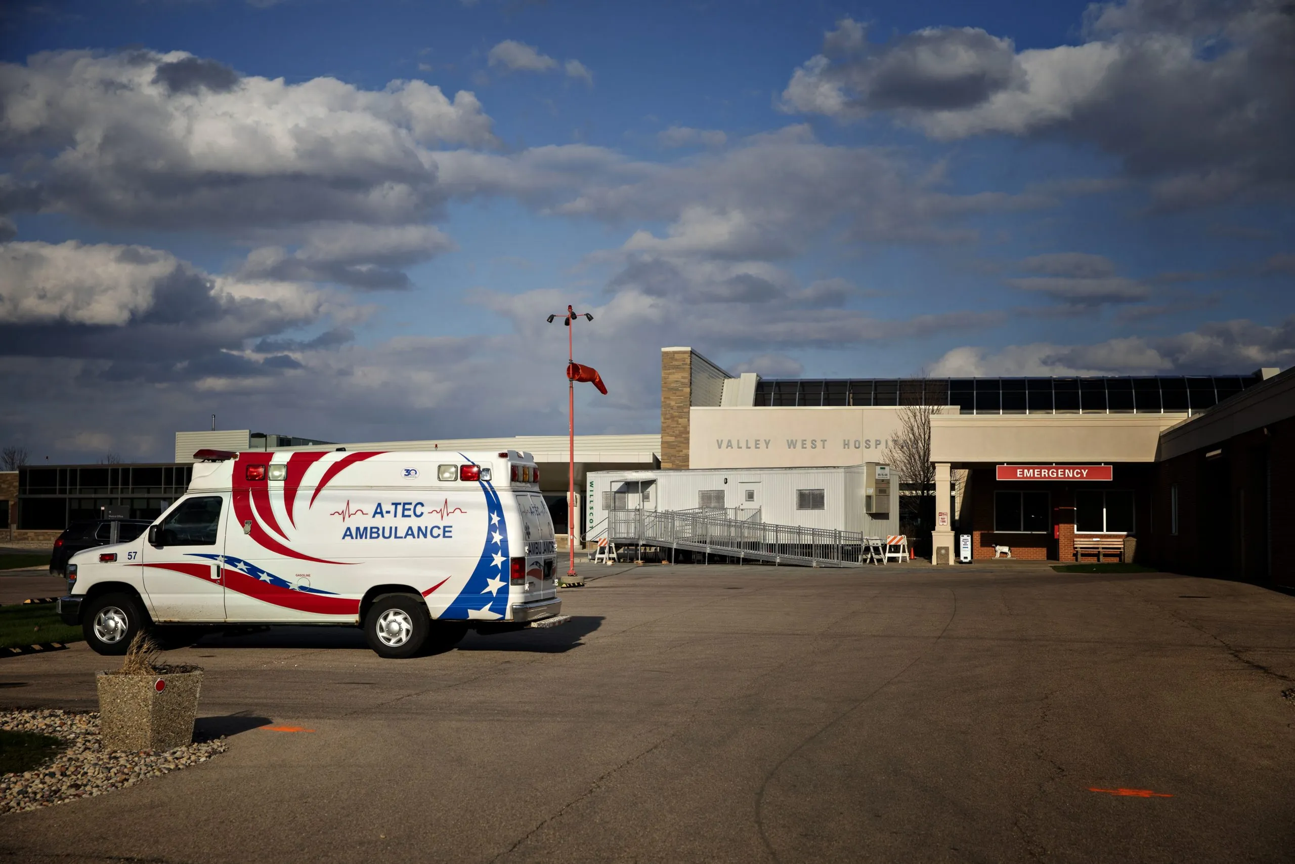 a hospital with an ambulance in the parking lot and an emergency sign