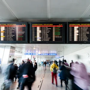 An airport terminal showing signs of international departures with people walking to and from below.