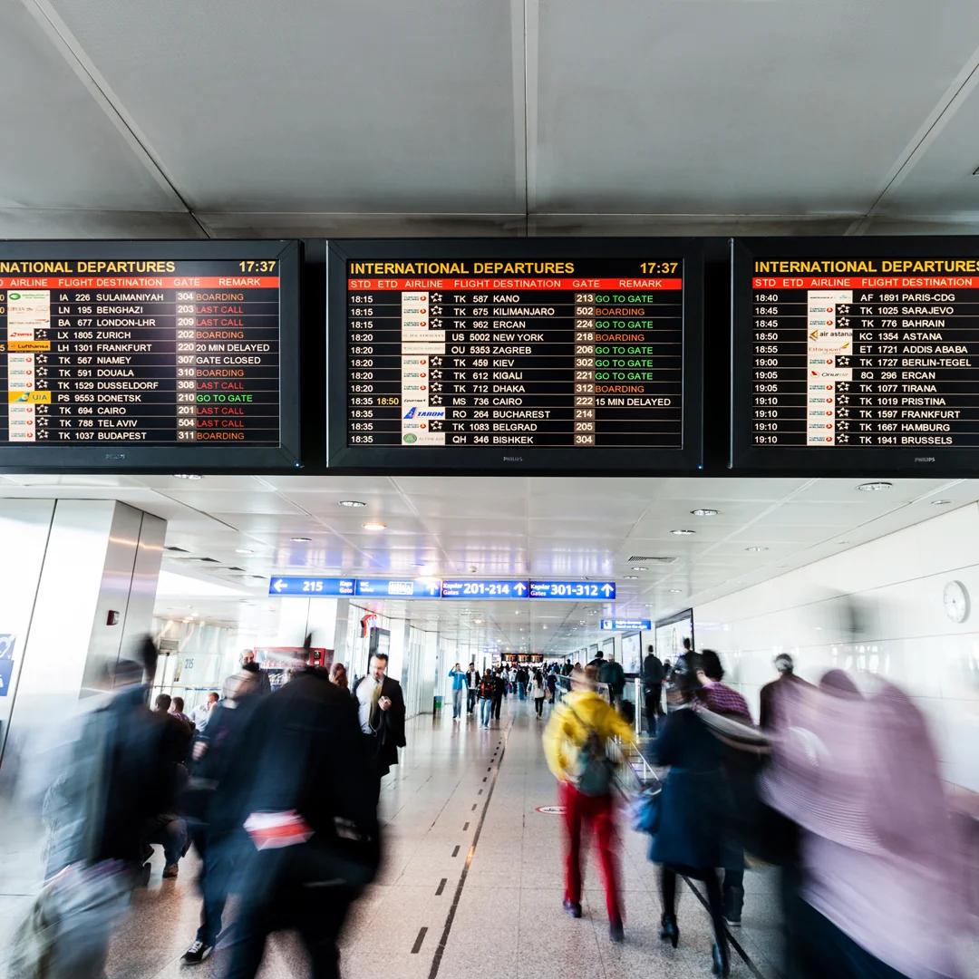 An airport terminal showing signs of international departures with people walking to and from below.