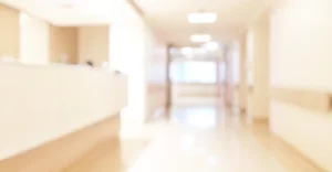 The inside of an empty hospital, showing a nursing station on the left and looking down the hallway towards a window