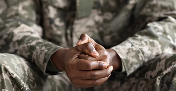 Person in military uniform clasps hands