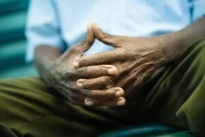 closeup of hands of elderly african american man sitting on bench