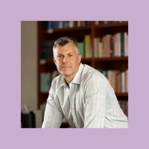 Headshot of James Tabery in a dress shirt in front of a bookshelf