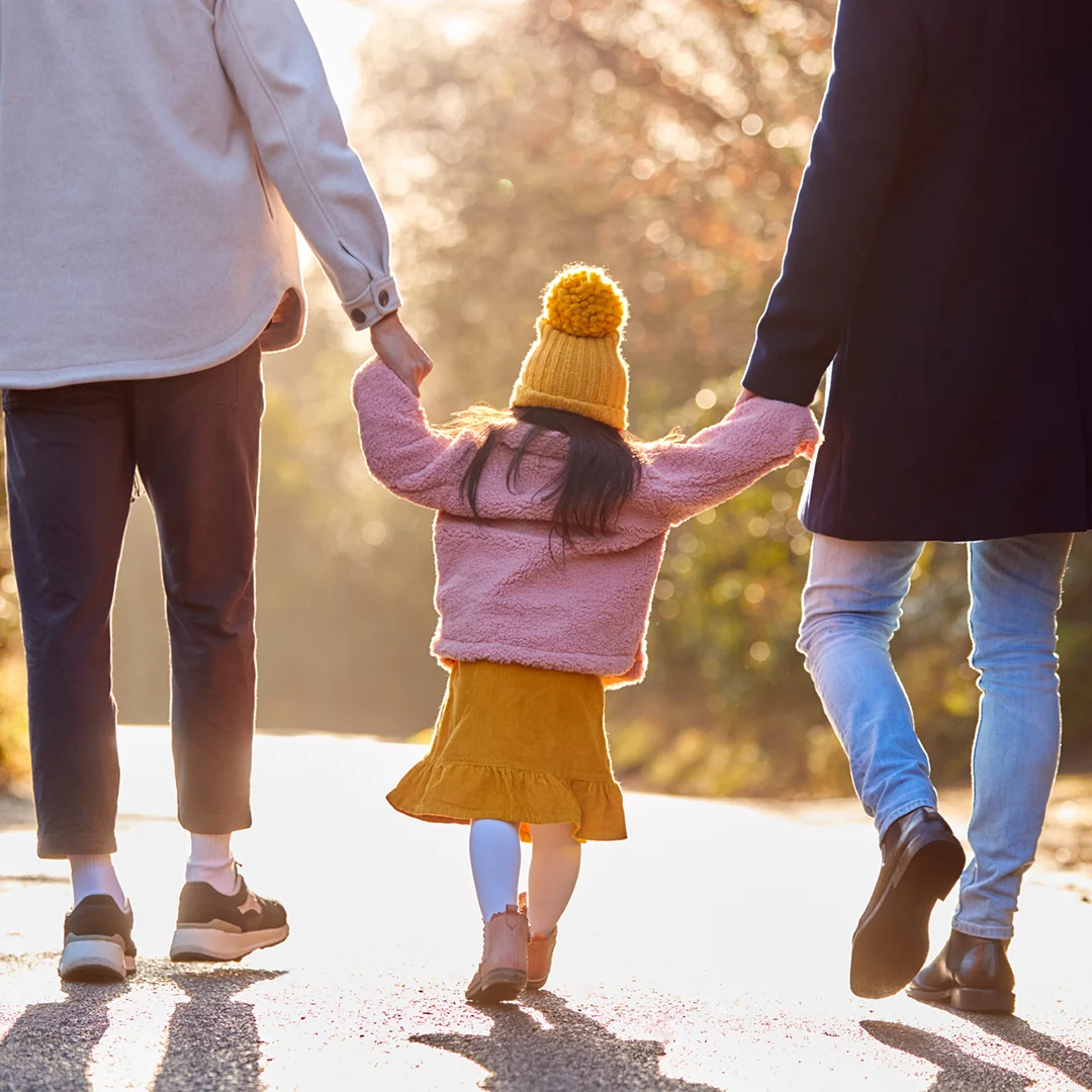 Child holds the hands of her LGBTQ+ parents